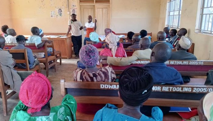 Mr Edson Akankwasa ,a cooperative extensionist demonstrating how to make an ethanol based trap for Black coffee twig borer during a farmer training session in Dwaniiro cooperative, Rakai district.